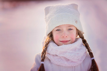 Portrait of a pretty little girl with snowflakes on her eyelashes on a frosty winter day. Close up