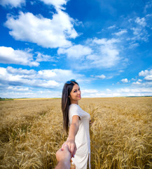 Come with me, young beautiful girl holds the hand of a man in a wheat field