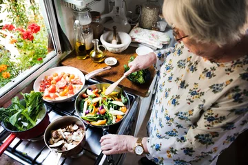 Crédence de cuisine en verre imprimé Cuisinier Femme âgée faisant cuire du couscous et des légumes sains dans une casserole