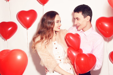 Man with his lovely sweetheart girl kiss at Lover's valentine day. Valentine Couple. Couple kiss and hug. On background red balloons hearts. Love concept. Lovers looking each other in eyes with love
