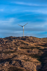 View of a wind turbine on top of mountains, dramatic sunset sky