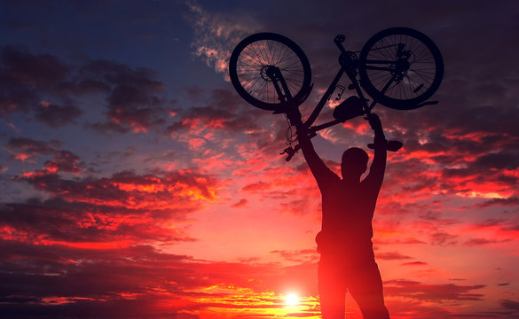 tourist with a bicycle on the background of a fiery sunset