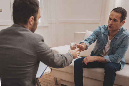 Helpful therapist handing glass of water to his stressed client