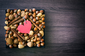 Obraz premium Paper heart shape on nuts background, top view