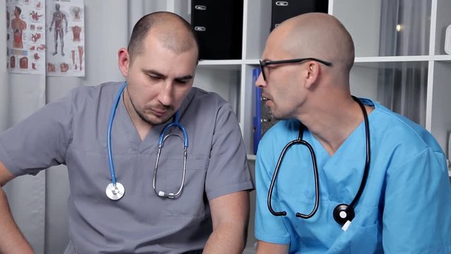 Male doctor and young intern in a good mood talking about new medical researchs