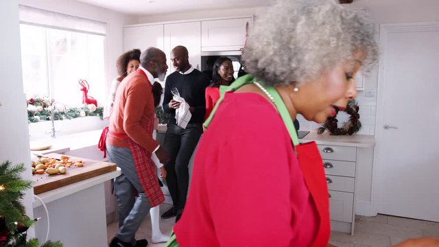 Mixed race, multi generation family talking in the kitchen while they prepare Christmas dinner together, panning shot