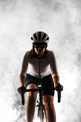 Obraz na płótnie Canvas female roadbiker riding a bicycle against fog background