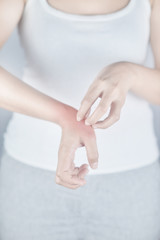 Woman scratching hand from itching on white background. Cause of itchy skin include insect bites, dermatitis, food/drugs allergies or dry skin. Concept of health care skin.