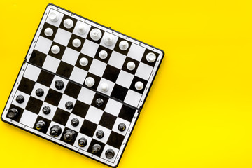Chess game concept. Chess board with figures on yellow background top view copy space