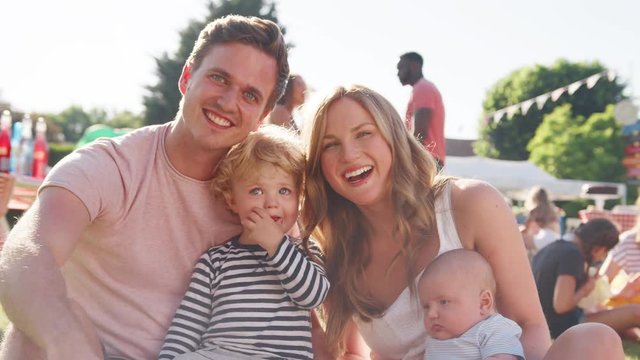 Slow Motion Portrait Of Family With Children Sitting On Grass At Summer Garden Fete