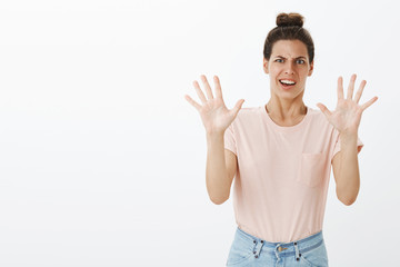 Displeased awkward and bothered young funny female with messy bun making grimace from aversion and...