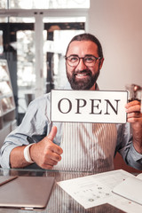 Happy shop owner holding the open sign