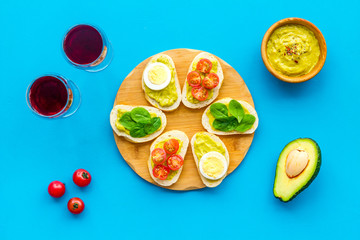 Healthy snacks. Set of toasts with vegetables like avocado, guacamole, rocket, cherry tomatoes on blue background top view
