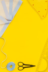 Hobby sewing with thread, scissors, fabric. Lifestyle. Yellow background top view mock up