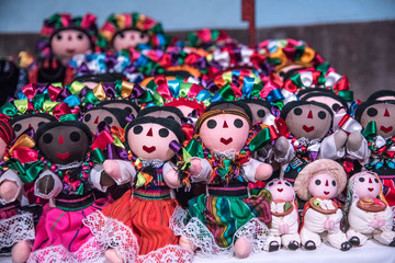 Fototapeta na wymiar muñecas mexicanas tradicionales, vestidas con listones coloridos y tiernas caras en un fondo colorido