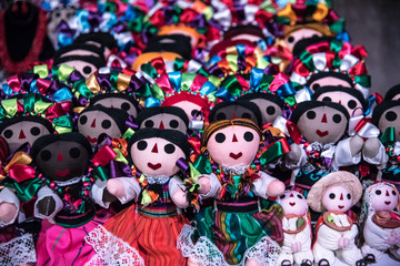 muñecas mexicanas tradicionales, vestidas con listones coloridos y tiernas caras en un fondo colorido