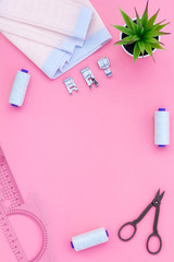 Tailor shop with thread, scissors, fabric. Sewing as hobby. Pink background top view mockup