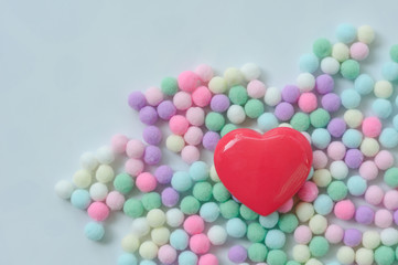 Red heart and pastel color pom poms background, valentine concept.