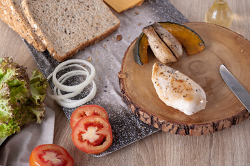 Grilled breast chicken on wooden chopping board with vegetable and whole grain bread cooking for breakfast