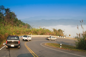 driving on curve road in the mountain with the sea mist and blue sky and forest, country road in north of Thailand