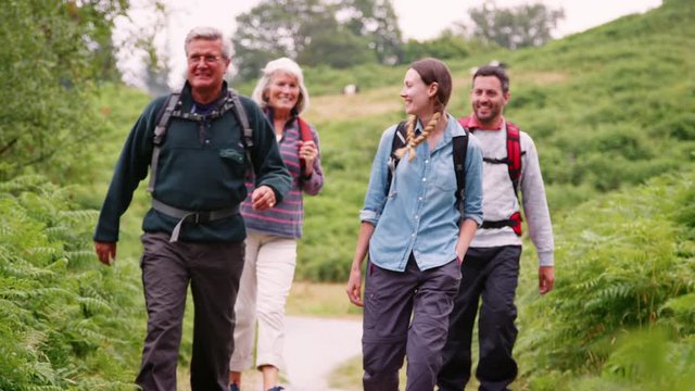 Two mixed age couples  walking on a countryside path during family camping adventure, Lake District, UK