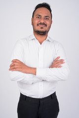 Studio shot of happy bearded Indian businessman smiling with arms crossed