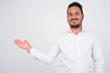 Studio shot of happy bearded Indian businessman showing something