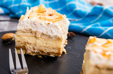 Homemade cake with whipped cream, almonds petals, toffi cream