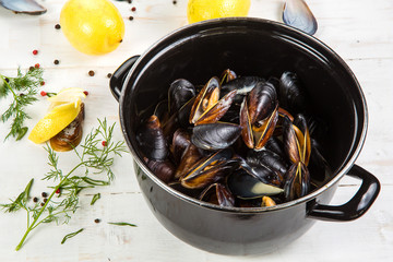 mussels in white wine sauce with glass of white wine , decorated with herbs, lemon and pepper