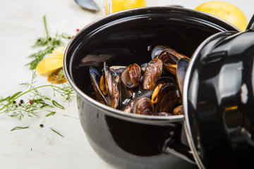 mussels in white wine sauce with glass of white wine , decorated with herbs, lemon and pepper