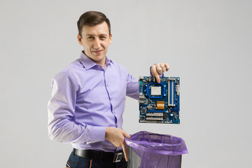 young man throws motherboard in trash isolated on light background