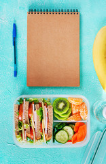 Schoollunchdoos met sandwich, groenten, water en fruit op tafel. Gezonde eetgewoonten concept. Plat leggen. Bovenaanzicht