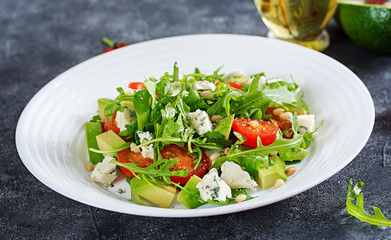 Dietary salad with tomatoes, blue cheese, avocado, arugula and pine nuts.