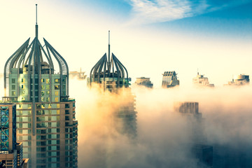 Aerial view of skyscrapers in the clouds. Morning winter fog over Dubai Marina skyline