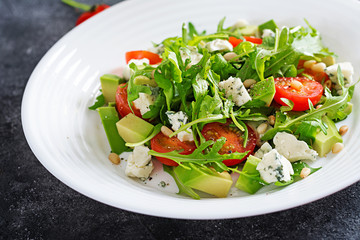 Dietary salad with tomatoes, blue cheese, avocado, arugula and pine nuts.