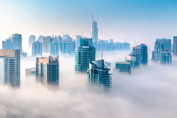 Aerial view of skyscrapers in the clouds. Morning winter fog over Dubai Marina. City above the clouds - Powered by Adobe