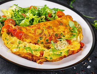 Breakfast. Omelette with tomatoes, avocado, blue cheese and green peas on white plate.  Frittata - italian omelet.