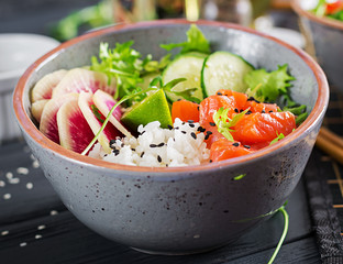 Hawaiian salmon fish poke bowl with rice, cucumber, radish, sesame seeds and lime. Buddha bowl. Diet food.