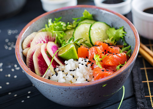 Hawaiian salmon fish poke bowl with rice, cucumber, radish, sesame seeds and lime. Buddha bowl. Diet food.