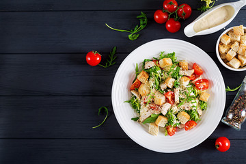 Healthy grilled chicken Caesar salad with tomatoes, cheese and croutons. North American cuisine. Top view