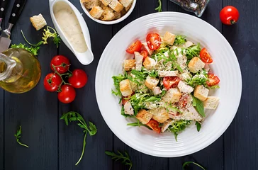 Fototapeten Healthy grilled chicken Caesar salad with tomatoes, cheese and croutons. North American cuisine. Top view © timolina