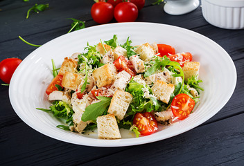 Healthy grilled chicken Caesar salad with tomatoes, cheese and croutons. North American cuisine.
