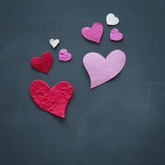 Valentine's day concept. pink and red paper hearts over blackboard.