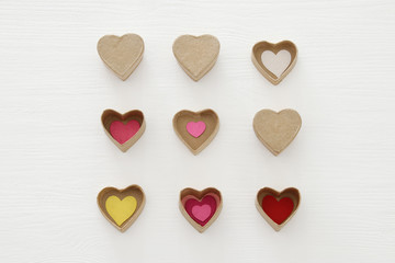 Valentine's day concept. hearts as paper gift boxes over wooden white background.