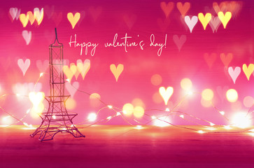 Fototapeta na wymiar Valentine's day background. Eiffel tower over wooden table and purple background.