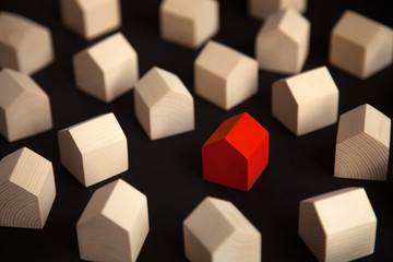 Many wooden houses with single red house in center. Red wooden house standing out from the crowd