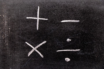 Hand drawing of white chalk in mathematics symbol shape (Plus, minus, multiply, divide) on black...