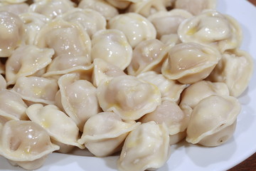 Hot Siberian dumplings with greens on a white plate