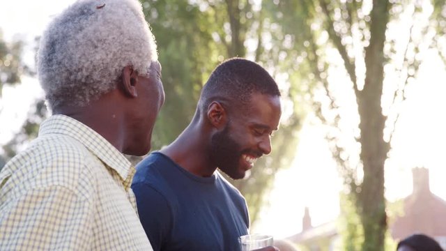 Grandad talks with his sons and grandson at family barbecue