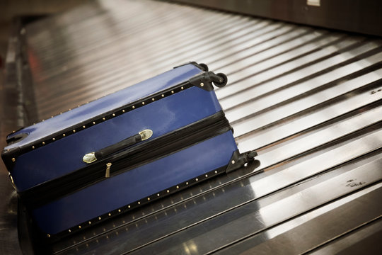 Suitcase on luggage conveyor belt at baggage claim area at airport terminal